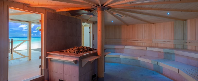A cozy sauna room featuring a wooden floor and a beach image, inviting relaxation and warmth.
