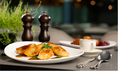 Dumplings served on a white plate surrounded by herbs and spices.
